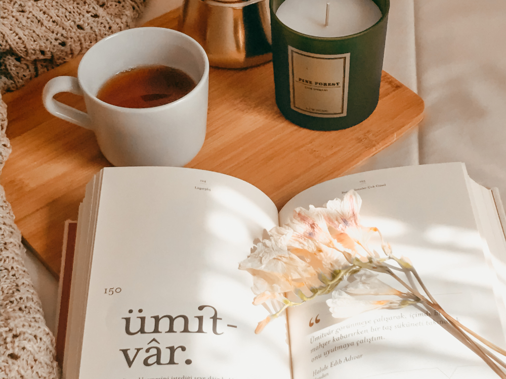 Help Write a Book service by Indelible Media - professional writer assisting a client with book writing, working together at a desk with a laptop, notebooks, and a stack of books.